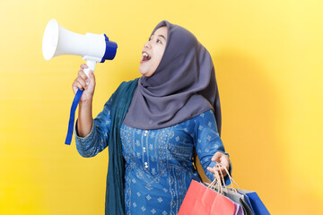 Woman in hijab shouting into megaphone with shopping bags.