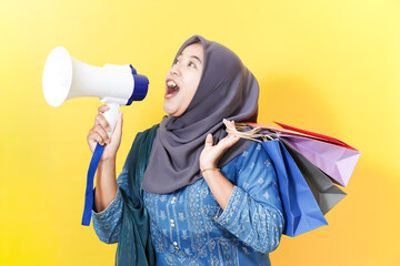 Woman in hijab shouting into megaphone with shopping bags.