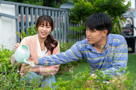 Young couple gardening together happily in backyard with watering can and plants