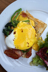 Close up eggs Benedict and bacon on toast served with green salad