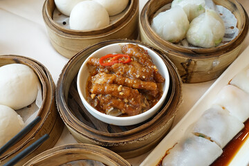 Noodle rolls and Braised Sichuan chicken feet served with Baozi in wooden basket, Steamed bun filled with various fillings mostly minced pork and sweet custard cream
