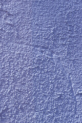 Vertical photo of a concrete wall with blue rough plaster.