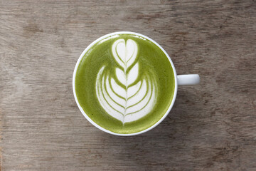 A cup of green tea matcha latte on wooden background                                          