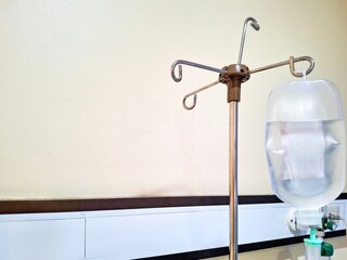Close-up of an IV drip bag hanging on a chrome infusion stand in a hospital room. Concepts: healthcare, medical treatment, patient care, and surgery recovery.