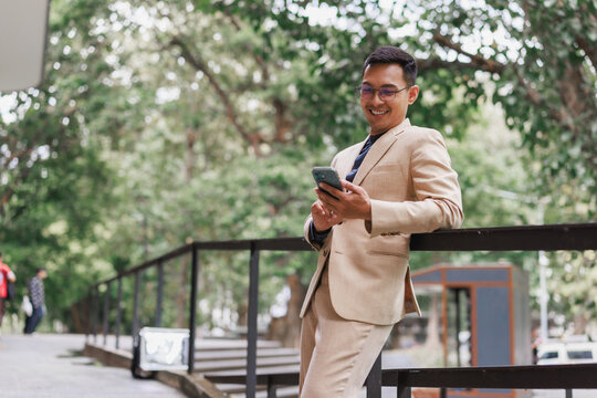 Businessman watching phone and smiling in urban park