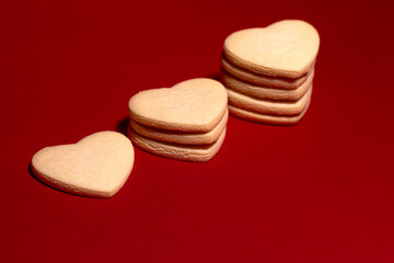 Stacked heart-shaped vanilla cookies on a red background, perfect for Valentine’s Day, romance, and sweet gifting concepts