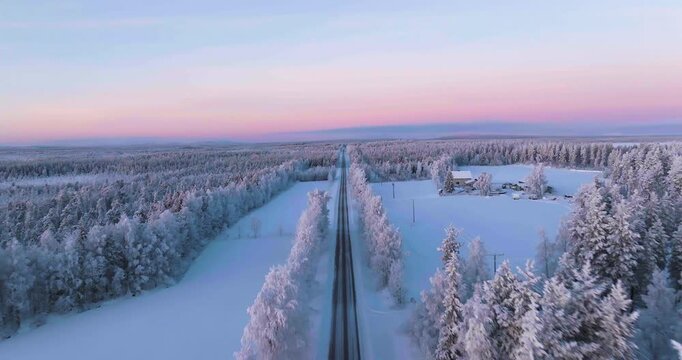 Aerial view backwards over a car driving on a frosty road in Lapland, polar night