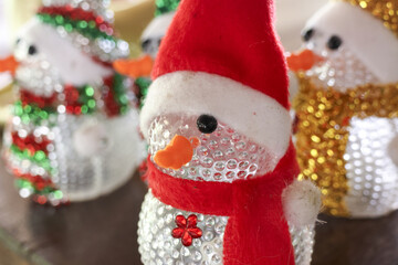 Cheerful snowman figurine wearing red santa hat and scarf as festive holiday decoration. This cute,...