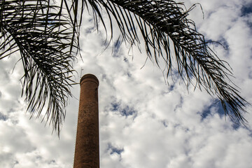 Chimney built with bricks, dry palm leaves and the sky with many clouds in the background, in Brazil