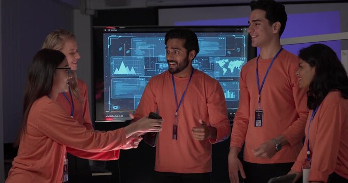 Product team in matching orange shirts collaborates around table, reviewing wireframes, color swatches, mobile app prototypes with analytics dashboards. Capturing UX UI sprint planning session
