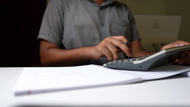 Person Calculating with Notebook on Desk