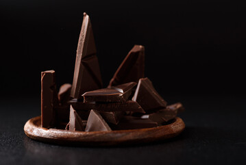 Small pieces of chocolate bars are arranged on a black background