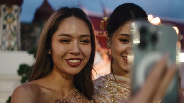Thai women in traditional clothing taking a selfie at wat arun