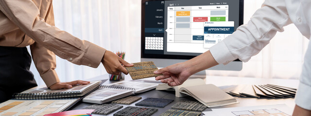 Group of interior architect designer team at table choosing various mood board samples with architecture software on laptop screen. Modern renovation and interior material selection concept. Insight