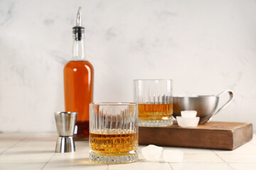 Glass of rum and ice cubes on table against blurred background. Closeup