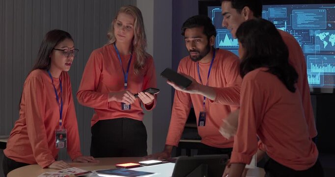 Product team in matching orange shirts collaborates around table, reviewing wireframes, color swatches, mobile app prototypes with analytics dashboards. Capturing UX UI sprint planning session
