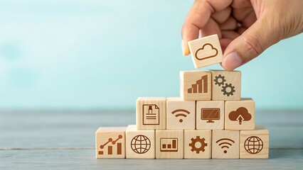 Hand placing a wooden block with a cloud icon on top of a pyramid structure made of blocks featuring various business, technology, and data icons, symbolizing digital transformation and strategy