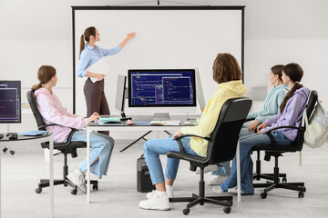 Teenage students with teacher studying at school computer lab, back view