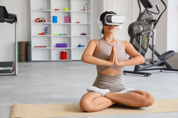 Sporty African-American woman in VR glasses meditating at gym