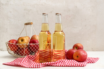 Bottles of fresh apple cider and basket with fruits on white background
