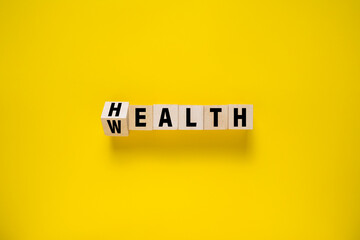 flip wooden blocks with wealth and health words isolated on yellow background