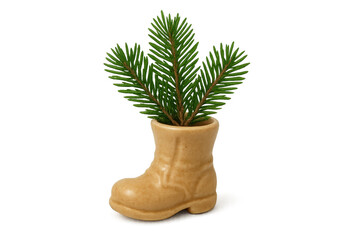 Fototapeta premium A small beige ceramic boot-shaped vase holding three fresh green fir branches for a minimalist Christmas decoration concept with a quirky and festive holiday mood