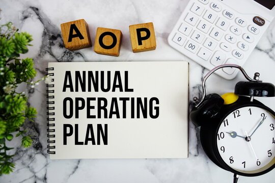 AOP Annual Operating Plan text with calculator and alarm clock on marble background