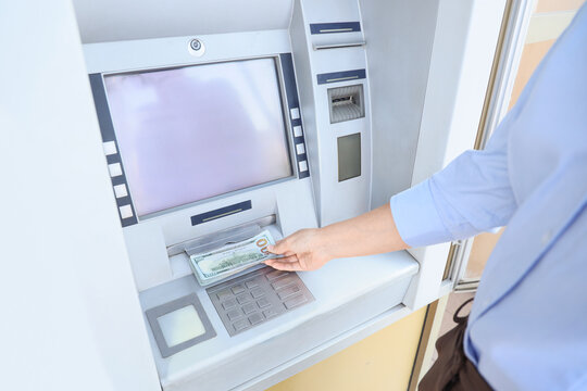 Businesswoman withdrawing dollar banknotes from ATM outdoors, closeup