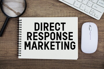Direct Response Marketing text written on notepad with keyboard, optical mouse and magnifying glass on wooden background