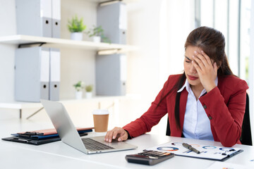 Asian businesswoman are serious at work causing headache stressed out with documents and laptop at the office.