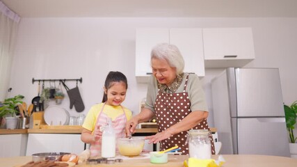 Asian granddaughter baking bakery with grandmother in kitchen at home. 