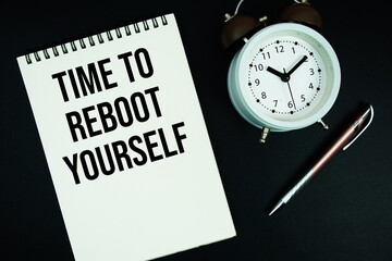 Time To Reboot Yourself text written on notepad with pen and alarm clock