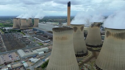 Low altitude drone reveal of thermal power station cooling towers belching steam and smoke at Selby UK