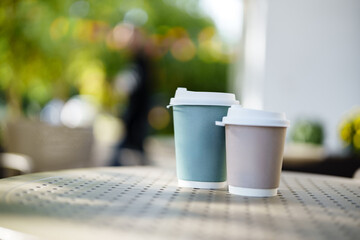 Coffee cups on a table in a sunny cafe garden during the afternoon