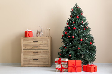 Decorated Christmas tree, chest of drawers and gift boxes in interior of living room