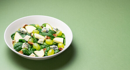 Salad with spinach, blue cheese, pear, grapes, and nuts. Healthy eating. Vegetarian.