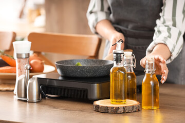Woman with sunflower oil frying food in kitchen, closeup