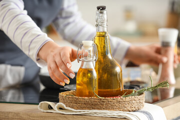 Woman taking sunflower oil from table in kitchen, closeup