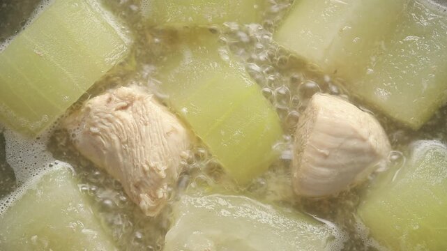 Winter melon and chicken meat simmering in a hot soup broth. Top view shot