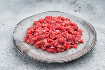 Fresh raw minced beef with thyme on a gray plate over concrete background ideal for recipe layouts negative space and food stock images.