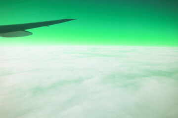 Surreal pop art of Airplane wing on the green sky with white clouds view from airplane during flight