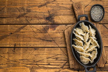 Steamed dumplings gyoza jiaozi mandu with sesame served in cast iron skillet on rustic wooden background Asian food top view.