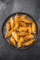 Crunchy gyoza wonton dumplings on dark stone background savory Asian dish with golden crust and sesame garnish