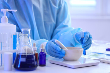 Young female chemist with mortar, pestle and test tube working in lab, closeup