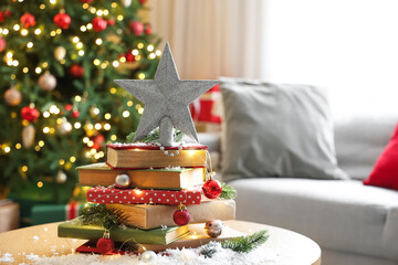 Wooden coffee table with Christmas baubles, glowing lights, snow and books in festive living room, closeup
