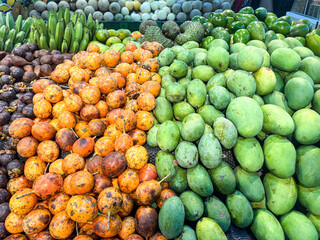 Vibrant market display of fresh tropical fruits green mangoes, exotic orange varieties, and purple mangosteens. Abundant, colorful produce highlighting healthy food choices
