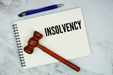 Insolvency text written on notepad with pen and judge gavel on marble background