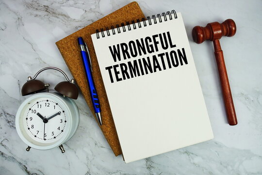 Wrongful Termination text written on notepad with pen and judge gavel on marble background