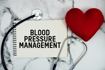 Blood Pressure Management text written on notepad with red heard and stethoscope on marble...