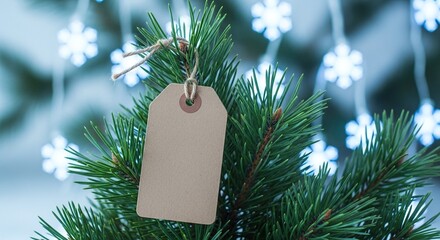 A blank rustic brown paper gift tag hangs on a green christmas tree branch, with blurred festive snowflake lights in the background, providing copy space for holiday messages